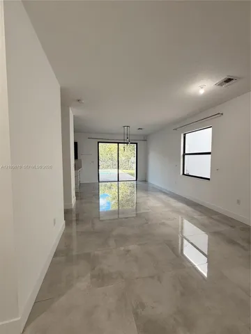 Open-concept interior featuring large-format tile flooring, recessed lighting, and sliding glass doors leading to the exterior