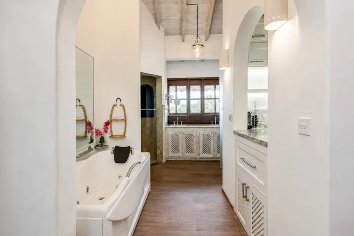 Bright bathroom featuring a vanity, arched architectural details, and neutral finishes.