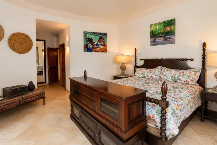 Comfortable bedroom featuring wooden furnishings, tropical-inspired décor, and warm lighting.