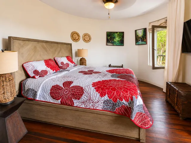 Welcoming bedroom with colorful floral bedding, wooden furnishings, and natural light.