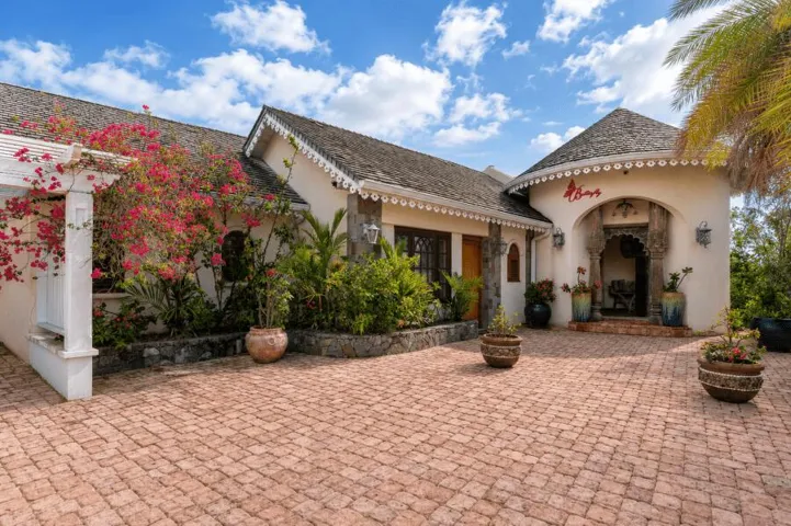 Charming villa entrance featuring a paved courtyard and vibrant tropical landscaping.ly Entrance