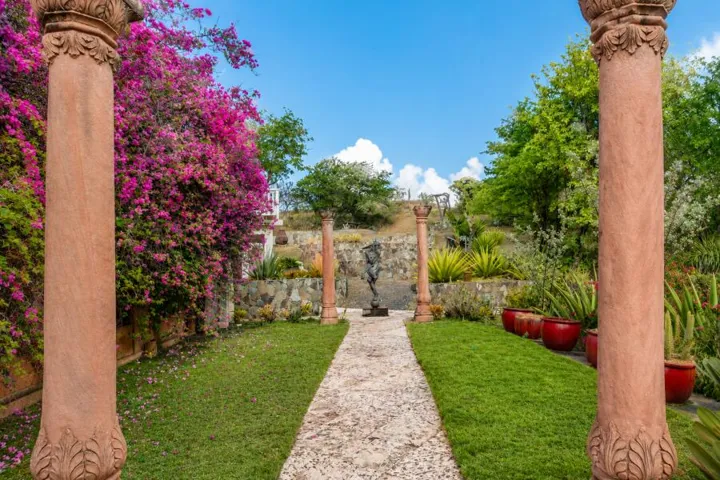 Inviting stone pathway surrounded by manicured lawns and vibrant tropical flowers.