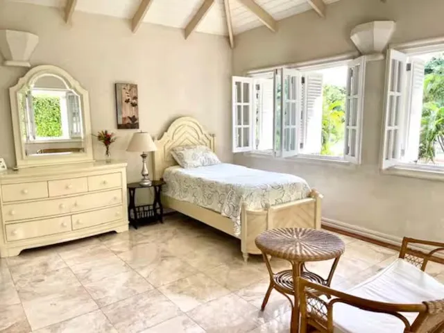 Bright bedroom with twin beds, vaulted ceilings, and multiple windows.
