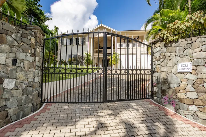 Attractive gated entrance featuring stone pillars and a paved driveway.