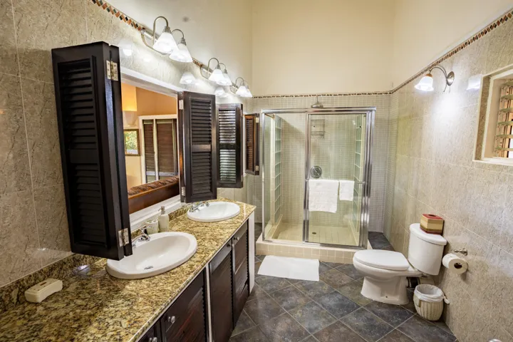 Well-appointed bathroom featuring a double-sink vanity, granite countertops, and a glass-enclosed shower.