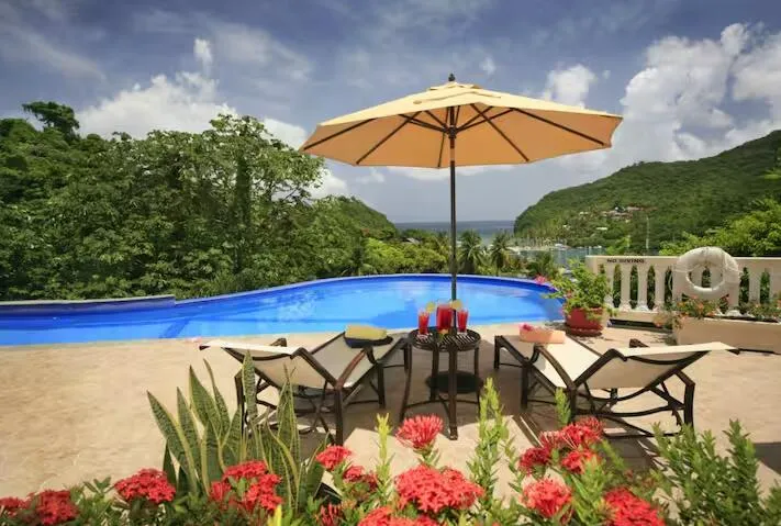 Inviting poolside retreat with lounge chairs, umbrella, and lush tropical landscaping.