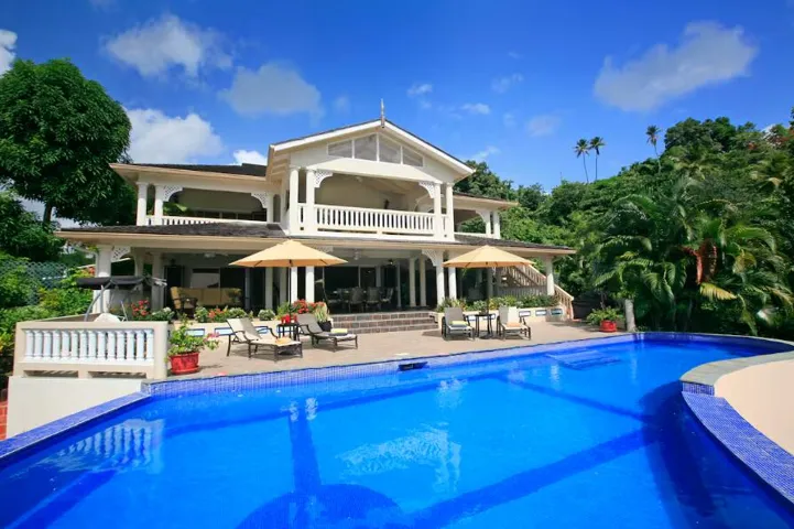 Expansive swimming pool with picturesque villa and lush greenery.