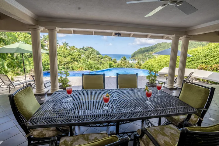 Beautiful outdoor dining space overlooking the pool and lush tropical landscape.