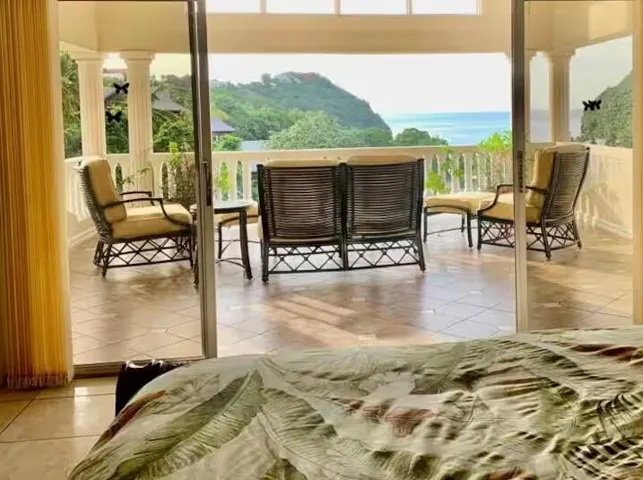 Beautiful bedroom opening to a covered terrace with scenic tropical views.