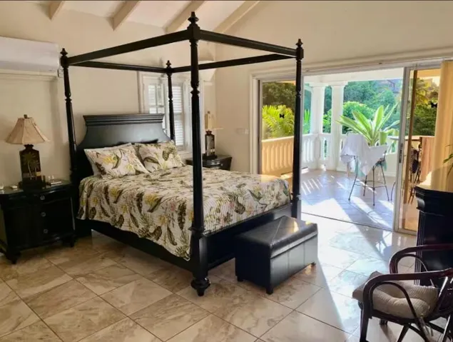 Beautifully furnished bedroom with a four-poster bed and tropical garden views.