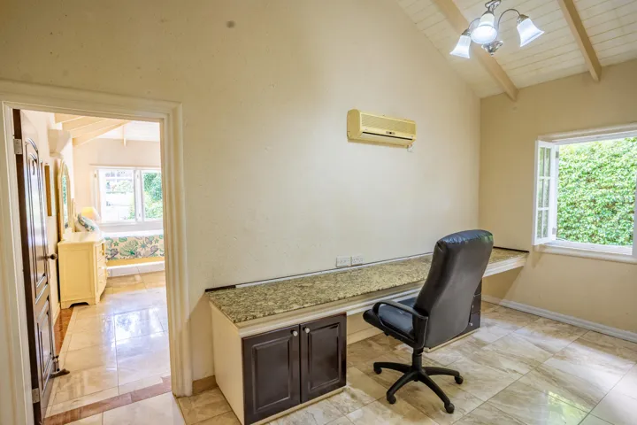 Bright home office featuring a built-in desk, vaulted ceiling, and natural light.