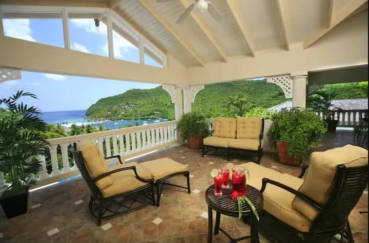 Inviting covered balcony with comfortable seating and scenic hillside views.