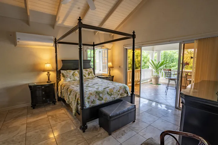 Inviting bedroom featuring a canopy bed and sliding glass doors overlooking lush greenery.
