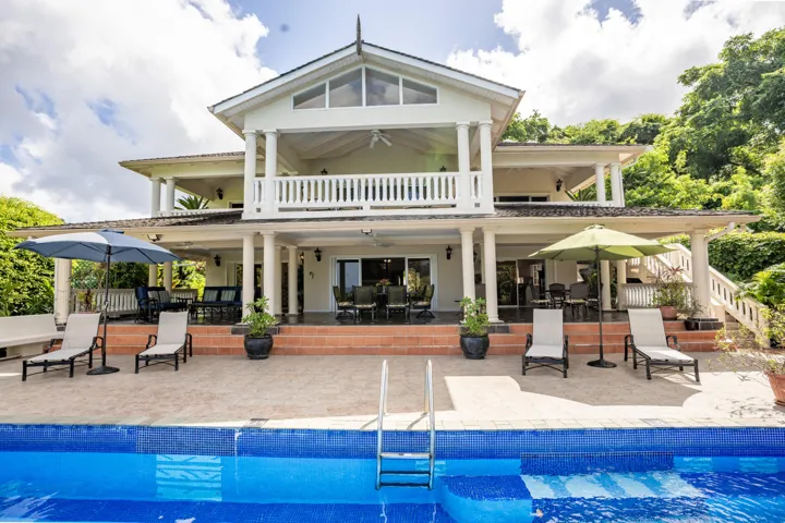 Stunning villa exterior with spacious pool deck and outdoor seating.