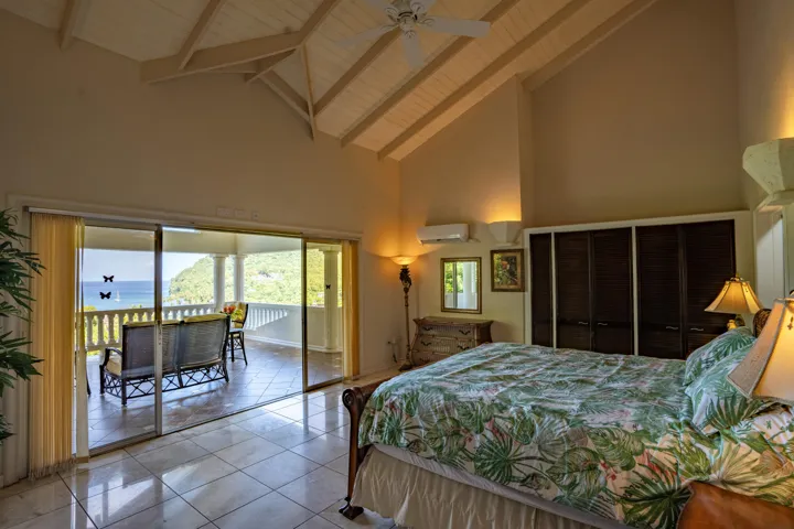 Inviting bedroom with vaulted ceilings and sliding glass doors leading outdoors.