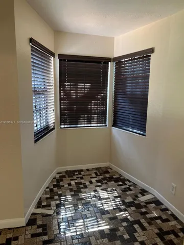Bay window featuring three operable windows with dark-finish horizontal blinds and mosaic tile flooring