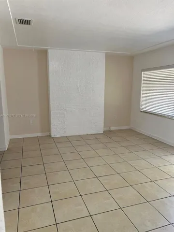 Interior space featuring large-format neutral tile flooring and a painted brick chimney breast