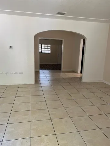 Neutral-toned tile flooring, distinctive arched architectural opening, and clean, light-colored walls
