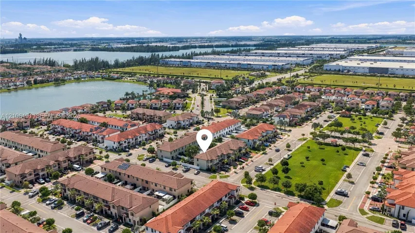 Aerial perspective of residential community featuring terra-cotta tile roofing, stucco exterior siding, paved street access, and water​​‌​​​​‌​​‌‌​‌‌​​​‌‌​‌​‌​‌​​​‌​​ features