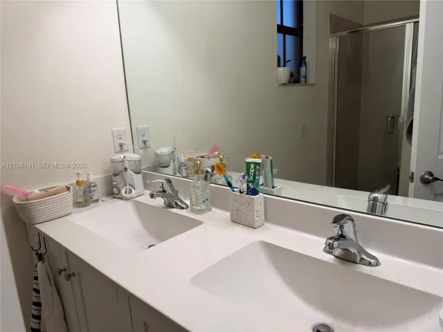Dual-sink vanity with white countertop, integrated basin sinks, chrome faucets, and large wall-mounted mirror