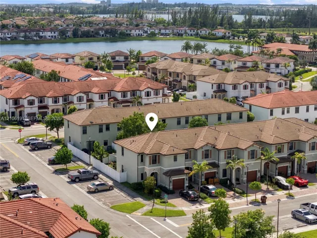 Multi-story residential unit featuring a neutral-toned stucco exterior, terracotta-style tiled roofing, an integrated single-car garage, and paved driveway