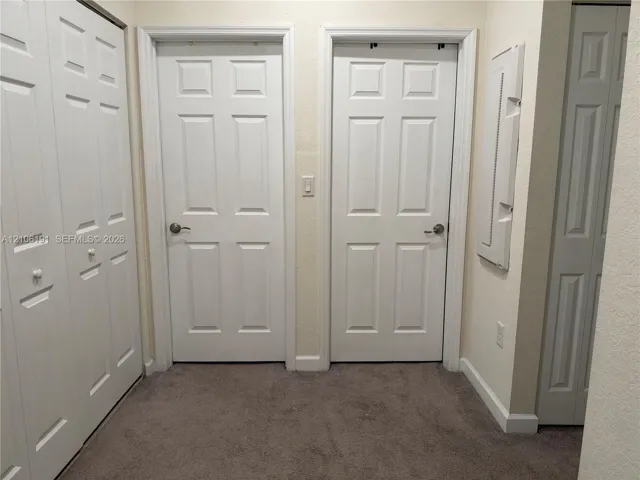 Interior space featuring neutral wall-to-wall carpeting, multiple six-panel interior doors, and built-in closet storage with bi-fold doors
