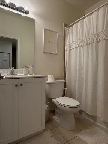 Bathroom featuring a white shaker-style vanity cabinet, large wall-mounted mirror, polished chrome faucet, and integrated lighting fixture above the mirror