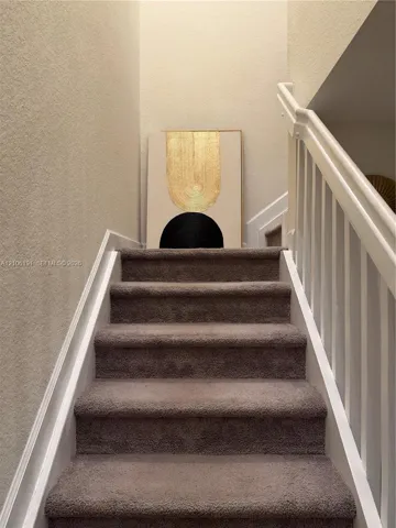 Staircase featuring wall-to-wall carpeting, white painted wooden balusters, and a matching handrail