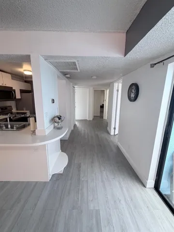 Kitchen featuring white cabinetry, wood-finish flooring, and a curved peninsula countertop