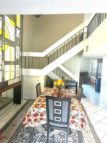 Staircase featuring a geometric metal railing, decorative stained-glass window panel, and high-gloss tile flooring