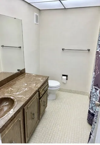 Vanity with stone-finish countertop and integrated sink, framed mirror, and tile flooring