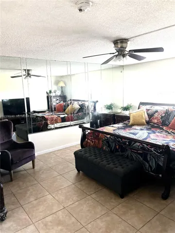 Full-wall mirrored accent, ceiling fan with integrated lighting, and neutral-toned tile flooring
