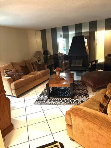 Ceramic tile flooring, black metal suspended fireplace, and floor-to-ceiling mirrored wall paneling