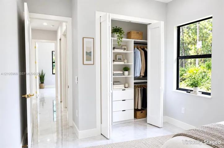 Built-in closet system with shelving and drawers, floor-to-ceiling bi-fold doors, large window with black frame, and polished tile flooring