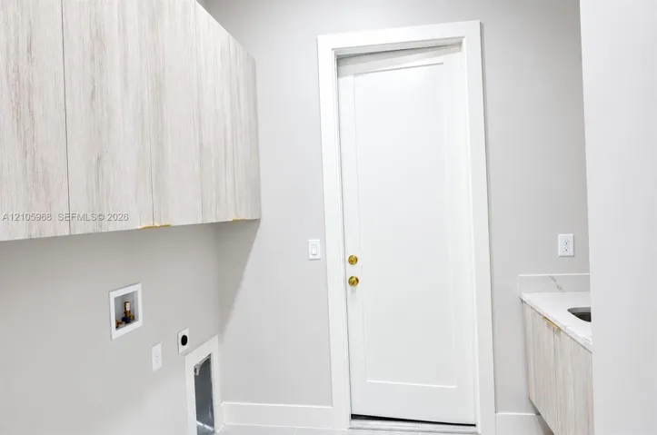 Wall-mounted wood-finish cabinetry, solid-core shaker-style door with brass hardware, stone-surface countertop, and built-in basin