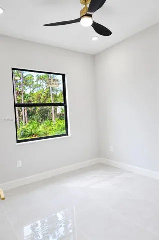 Interior space featuring large-format tile flooring, a modern three-blade ceiling fan with integrated light, recessed lighting, and a window with a black frame