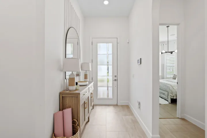 Entryway featuring large-format tile flooring, a glass-panel entry door, vertical wall paneling, and a recessed ceiling light
