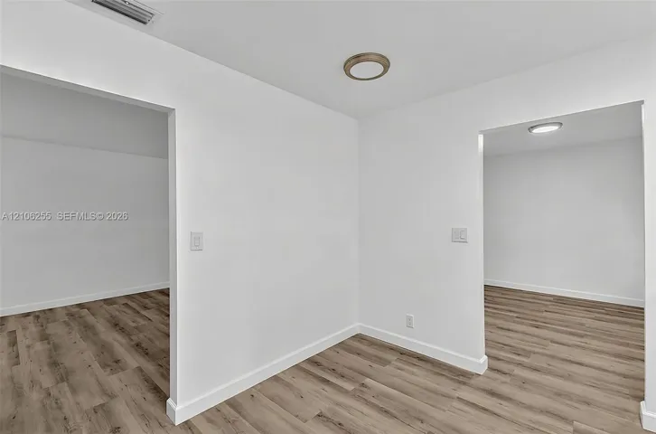 Neutral interior featuring wood-finish flooring, white walls, and flush-mount ceiling lighting