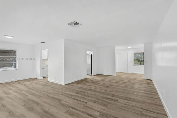 Open-concept interior featuring wood-finish flooring, crisp white walls, flush-mount lighting, and dual windows