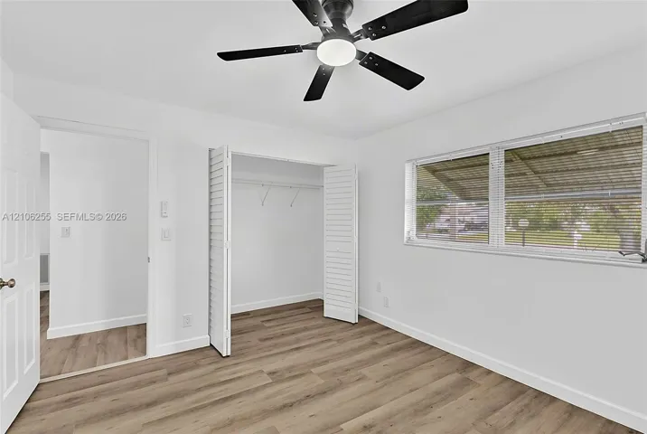 Room interior featuring wood-finish flooring, a ceiling fan with integrated lighting, and a closet with bifold louvered doors