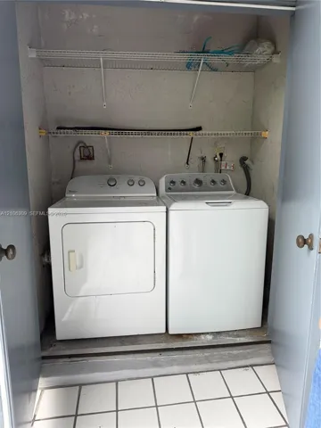 Laundry closet featuring white tile flooring and dual integrated wire shelving units