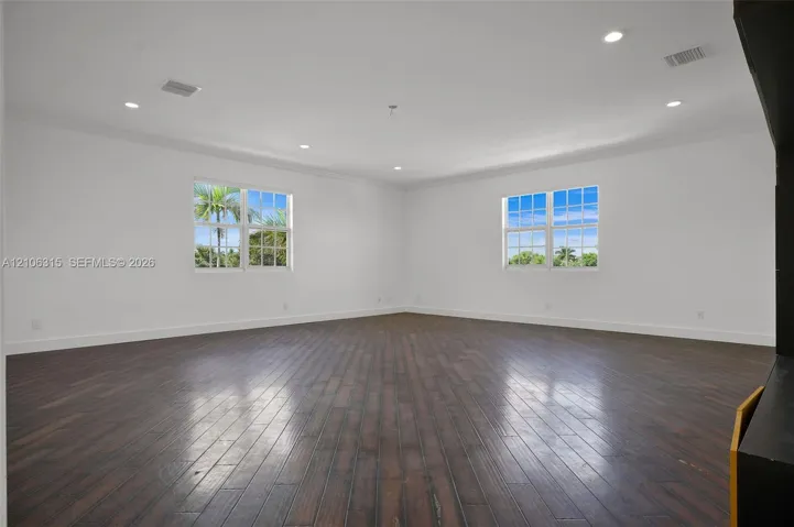 Expansive living area featuring wood-finish flooring, recessed lighting, crown molding, and large grid-patterned windows