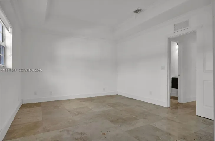 Neutral-toned tile flooring, recessed tray ceiling with crown molding, and a multi-panel door