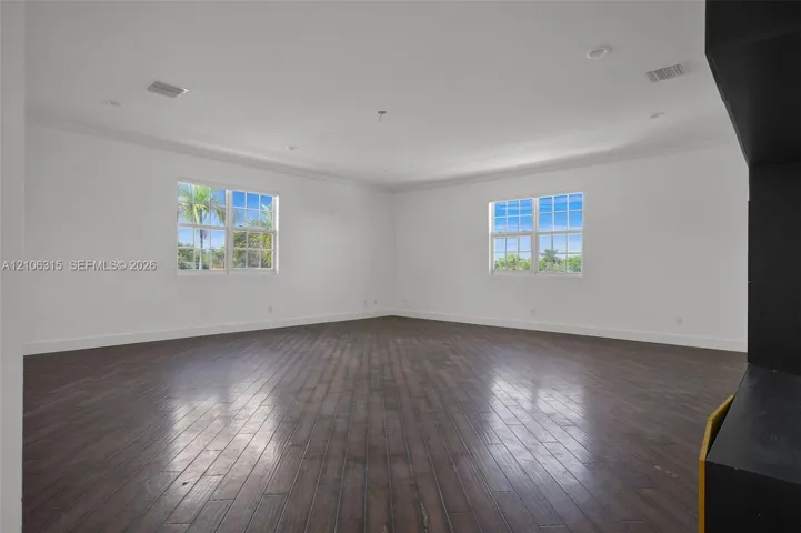Interior space featuring dark wood-finish flooring, multi-pane windows, recessed lighting, and crown molding