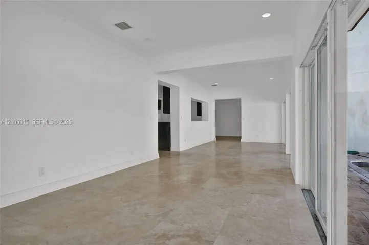 Neutral-toned large-format tile flooring, recessed ceiling lighting, and expansive multi-panel sliding glass door system