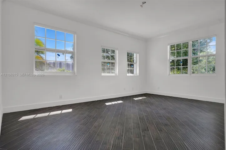 Interior space featuring dark wood-finish flooring, white walls, and multiple multi-pane windows with grid detailing