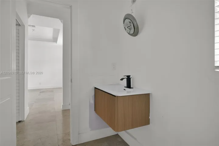 Wall-mounted floating vanity with reeded wood-finish cabinetry, white countertop, and matte black single-handle faucet