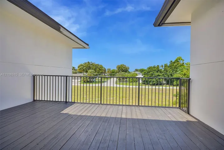 Covered outdoor deck featuring wood-finish decking, dark metal railings, and neutral exterior walls