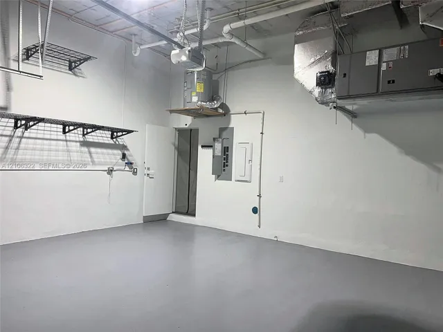 Finished garage space with epoxy-coated flooring, white interior walls, mounted wire shelving, ceiling-mounted HVAC unit, and an elevated water heater