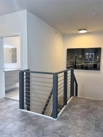 Contemporary cable railing with dark-finish posts, large-format neutral floor tile, and flush-mount ceiling lighting